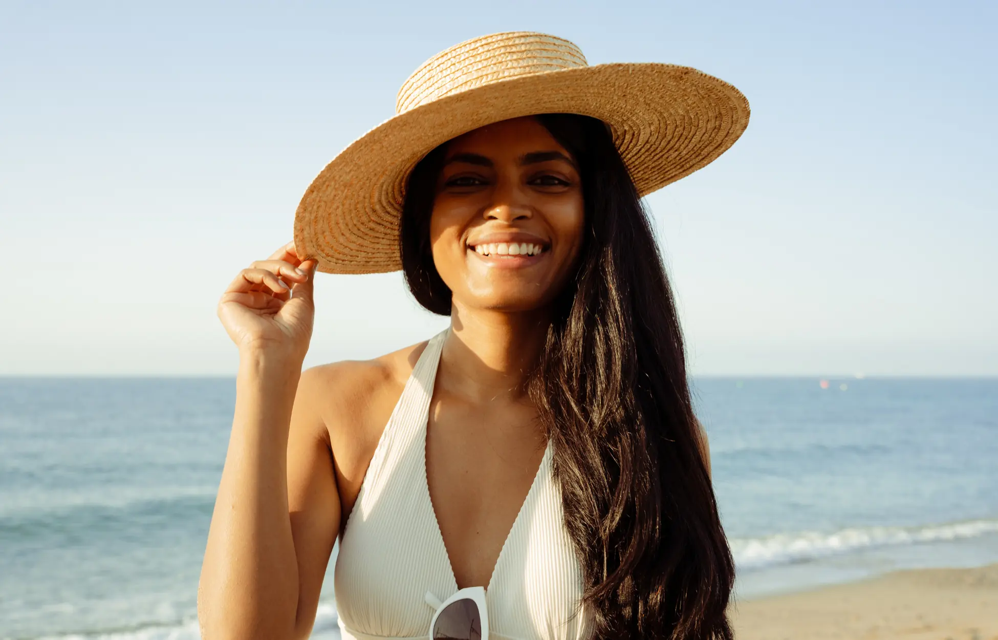 Jeune femme près de l'océan avec un chapeau de paille