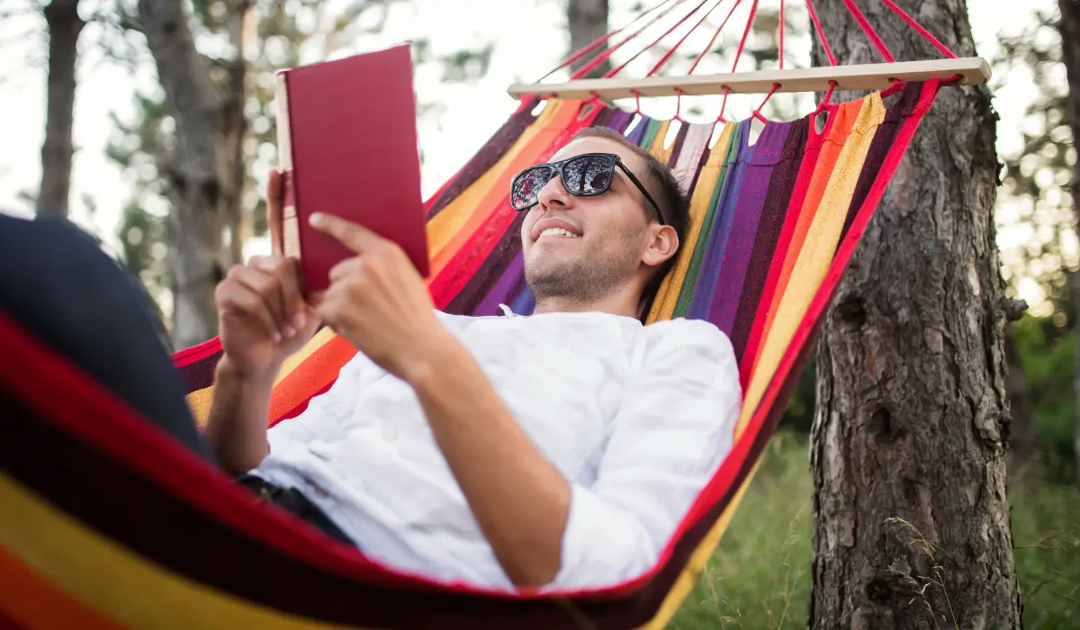 Homme en train de lire dans un hamac